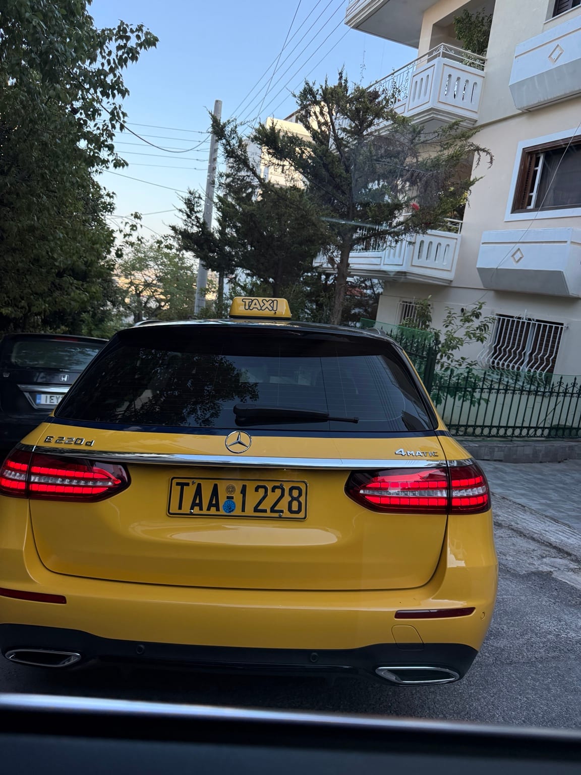 Rear view of the yellow Mercedes-Benz E 220 d 4MATIC taxi with its illuminated TAXI roof sign and Greek licence plate